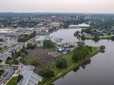Aerial Image overlooking Peterborough Musicfest for Little River Band Performance in Summer 2023. Crowd Arriving, daylight, city in the background.
