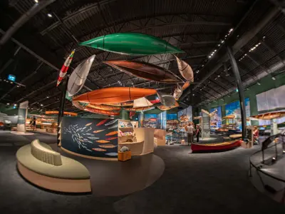 A view inside the Canadian Canoe Museum, many canoes suspended in the air on display