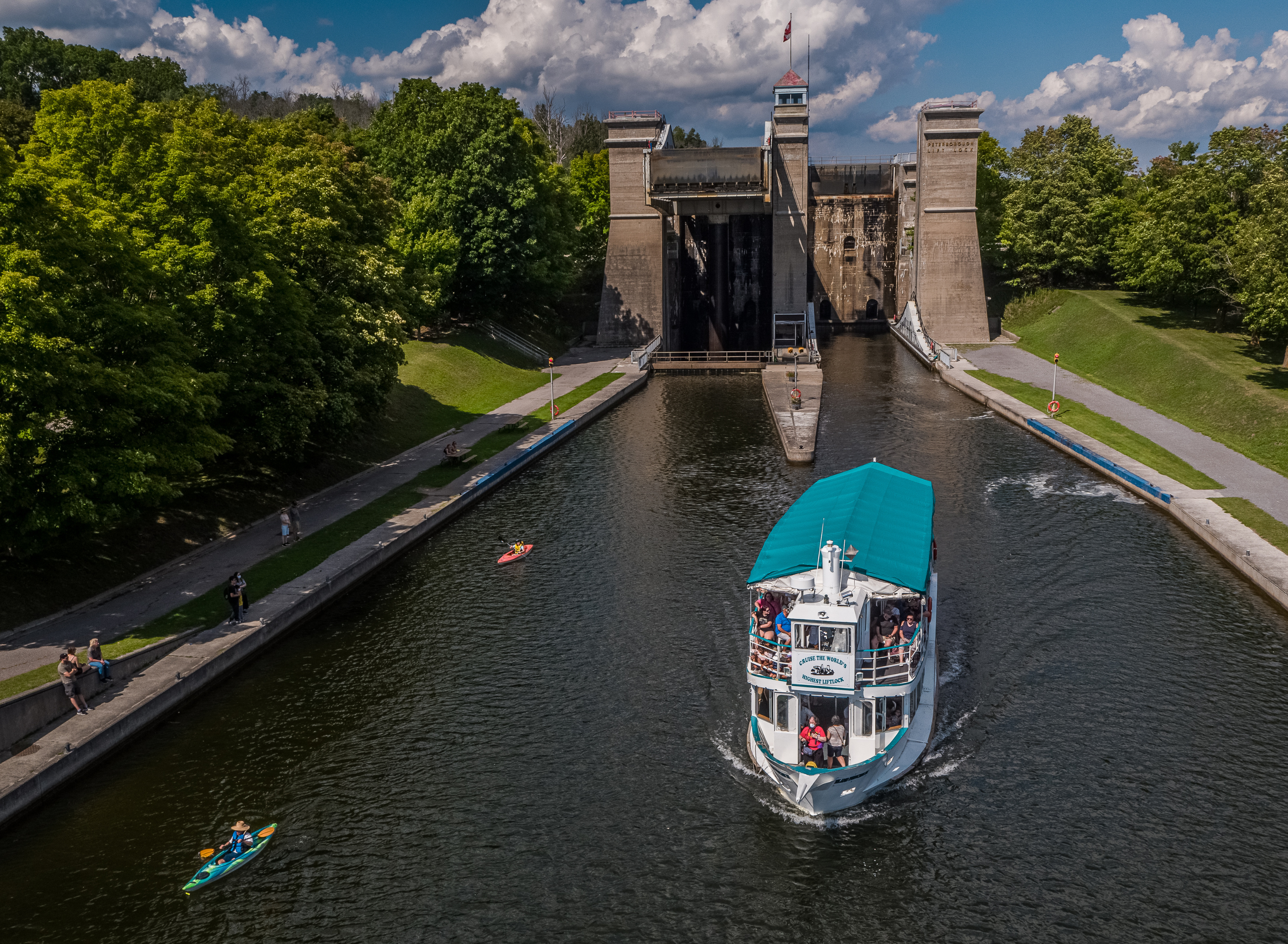 Large boat sailing down the river with the Peterborough Liftlocks in the background